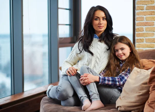 漂亮的小女孩和她的母亲坐在沙发上 — 图库照片