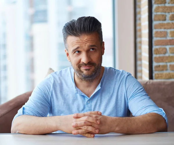 Bonito homem sentado à mesa em casa — Fotografia de Stock