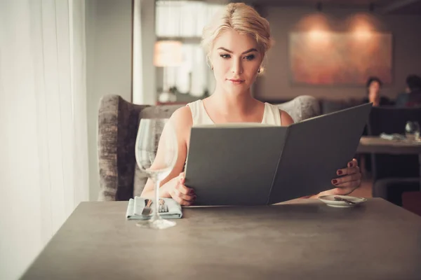 Mujer rubia elegante con menú en un restaurante — Foto de Stock