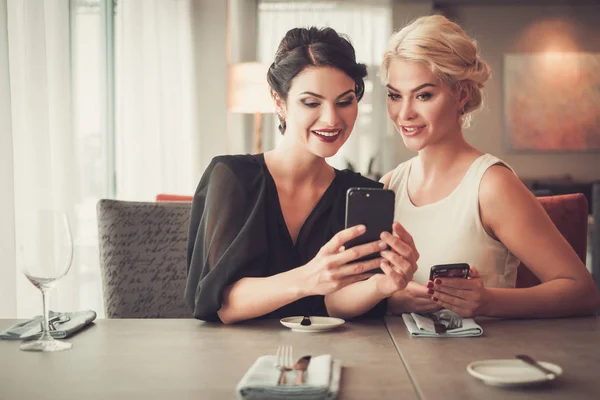 Duas senhoras elegantes tirando selfie no restaurante — Fotografia de Stock