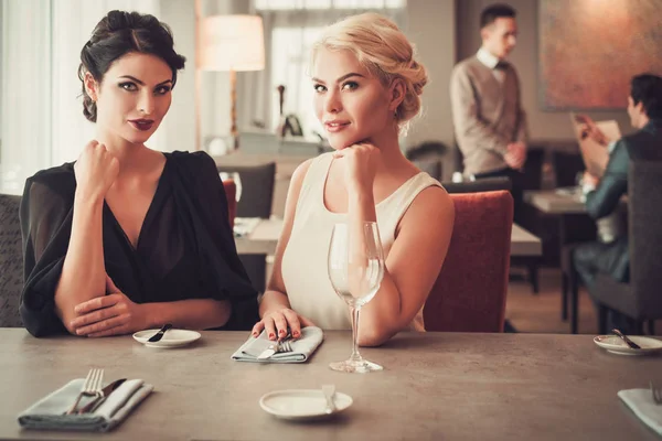 Dos señoras encantadoras en elegantes vestidos de noche en el restaurante —  Fotos de Stock