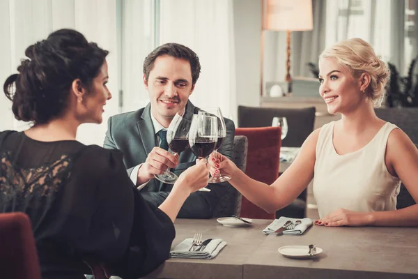 Grupp av rika människor klirrande glas rött vin i restaurang — Stockfoto