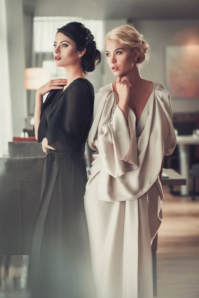 Duas senhoras encantadoras em vestidos de noite elegantes no restaurante — Fotografia de Stock