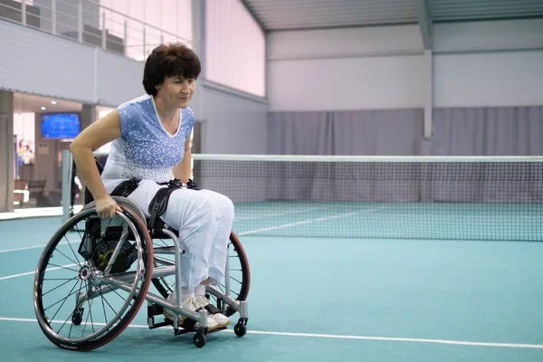 Disabled mature woman on wheelchair on tennis court — Stock Photo, Image