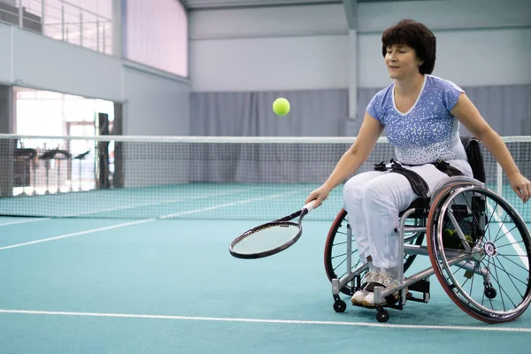 Зріла жінка на інвалідному візку грає в теніс на тенісному корті — стокове фото