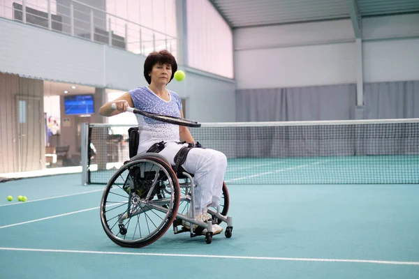 Άτομα με ειδικές ανάγκες ώριμη γυναίκα σε αναπηρικό καροτσάκι να παίζει τένις στο γήπεδο τένις — Φωτογραφία Αρχείου