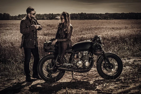 Young, stylish cafe racer couple on vintage custom motorcycles in field — Stock Photo, Image