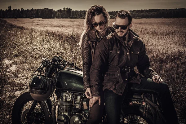 Young, stylish cafe racer couple on vintage custom motorcycles in field — Stock Photo, Image