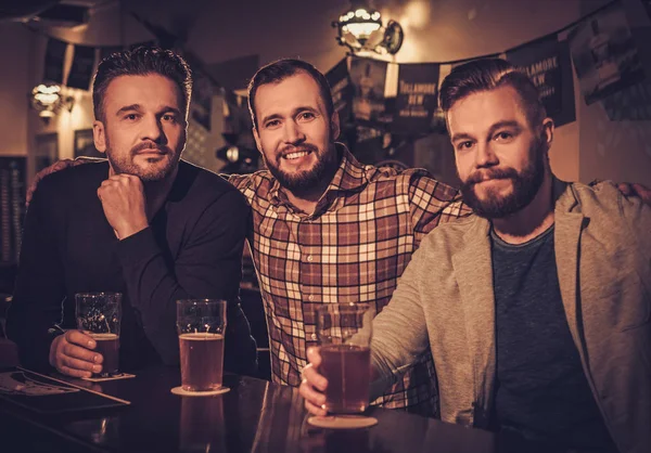 Cheerful old friends drinking draft beer at bar counter in pub. — Stock Photo, Image