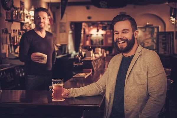 Uomo elegante seduto da solo al bancone del bar con una pinta di birra leggera . — Foto Stock