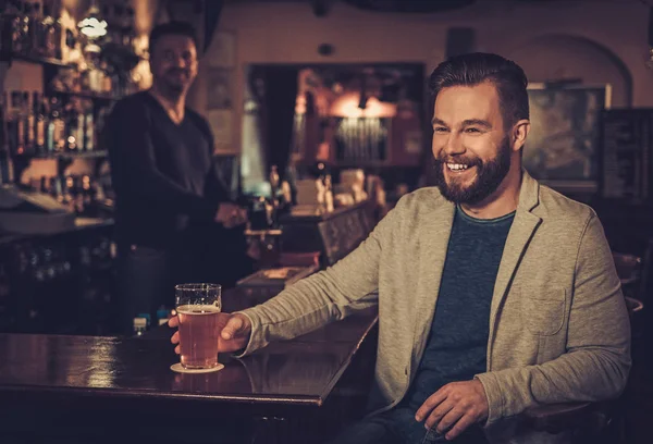 Uomo elegante seduto da solo al bancone del bar con una pinta di birra leggera . — Foto Stock