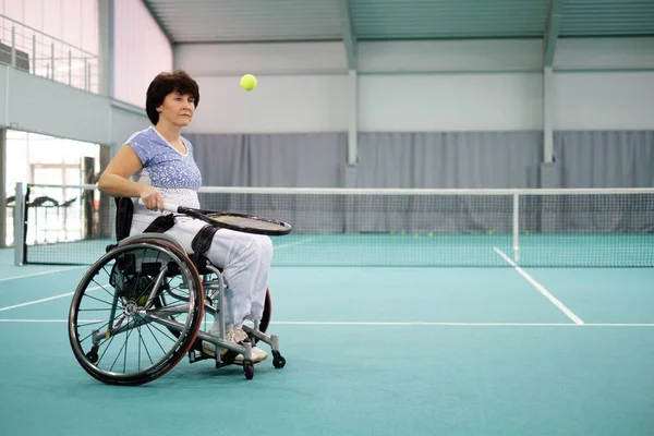 Mujer madura discapacitada en silla de ruedas jugando tenis en pista de tenis . —  Fotos de Stock