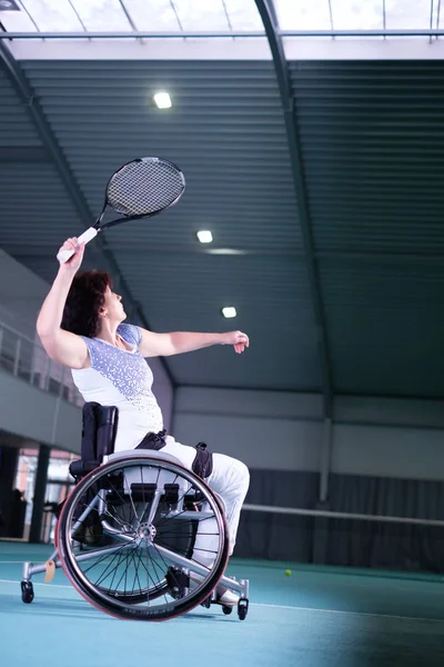 Disabled mature woman on wheelchair playing tennis on tennis court. — Stock Photo, Image