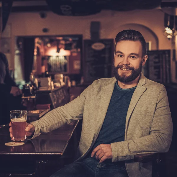 Wesoły człowiek stylowy przy kuflu piwa z beczki w licznik w pub bar. — Zdjęcie stockowe