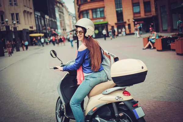 Young cheerful girl near scooter in in european city — Stock Photo, Image