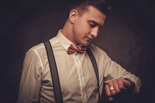 Гострий одягнений чоловік носить краватку з бантом, дивлячись на наручний годинник — стокове фото