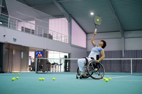 Disabled mature woman on wheelchair playing tennis on tennis court. — Stock Photo, Image