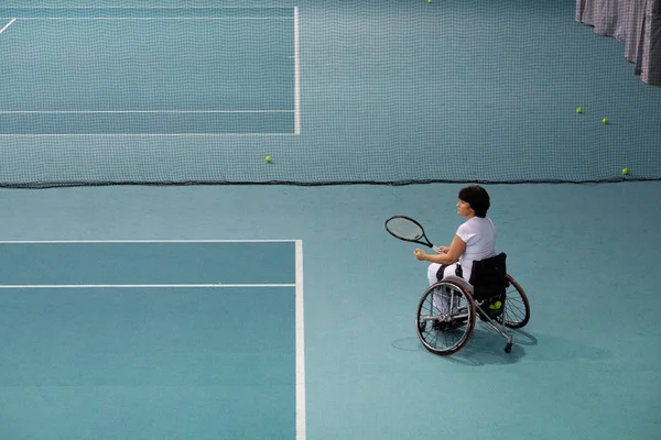 Άτομα με ειδικές ανάγκες ώριμη γυναίκα σε αναπηρικό καροτσάκι να παίζει τένις στο γήπεδο τένις. — Φωτογραφία Αρχείου