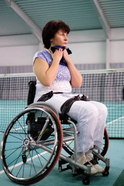 Moe van gehandicapte volwassen vrouw op de rolstoel op de tennisbaan. — Stockfoto