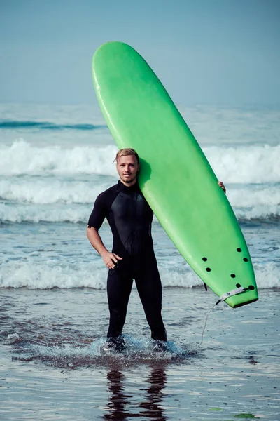 Szörfös viselt ruha áll egy szörf a strandon — Stock Fotó
