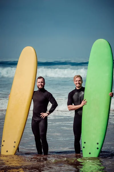 Surferanfänger und Surflehrer am Strand mit einem Surfbrett — Stockfoto