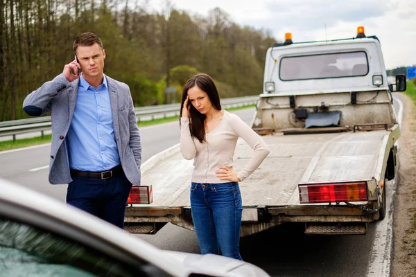 Pareja cerca de coche roto en una carretera — Foto de Stock