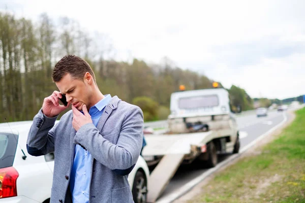 Homem chamando enquanto reboque caminhão pegando seu carro quebrado — Fotografia de Stock