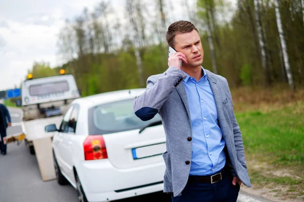 Man calling while tow truck picking up his broken car — Stock Photo, Image