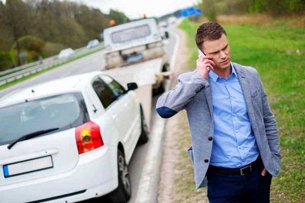 Man calling while tow truck picking up his broken car — Stock Photo, Image