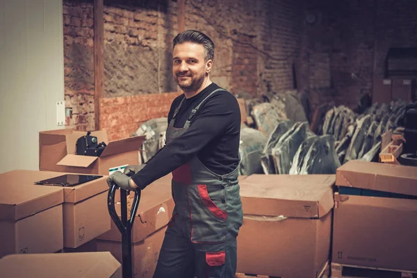 Almacenador trabajando con transpaleta en un almacén — Foto de Stock