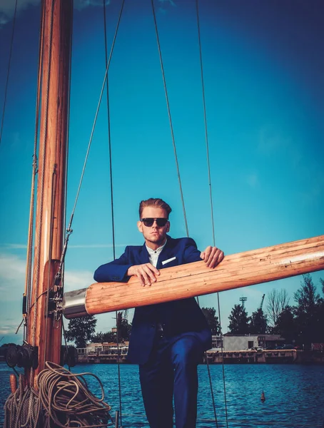 Stylish wealthy man on a luxury wooden regatta — Stock Photo, Image