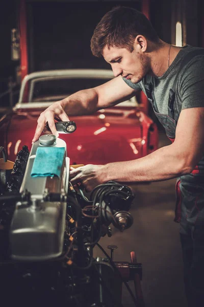 Mecânico de trabalho no motor de carro clássico na oficina de restauração — Fotografia de Stock