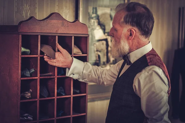 Senior man choosing custom made bow ties and neckties.