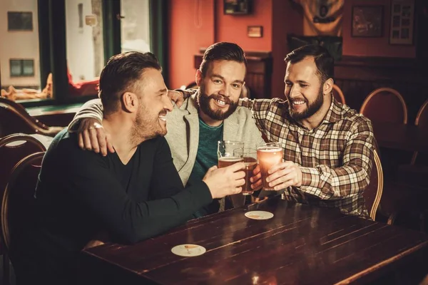 Cheerful old friends having fun and drinking draft beer in pub.