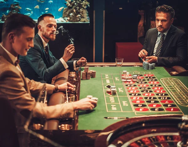 Amigos de classe alta jogando em um cassino — Fotografia de Stock