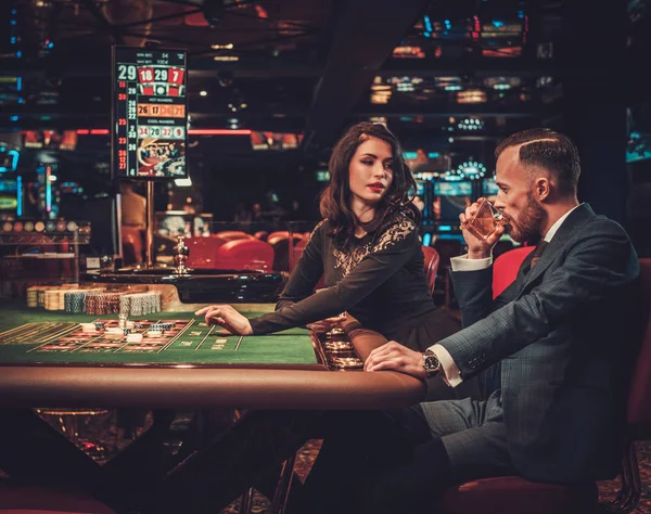 Pareja de clase alta apostando en un casino — Foto de Stock