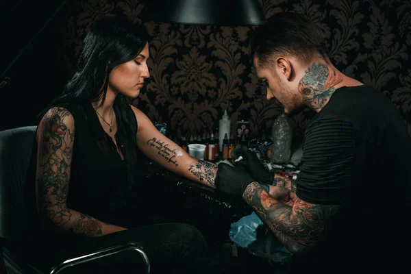 Artista profesional del tatuaje hace un tatuaje en una mano de chicas jóvenes —  Fotos de Stock