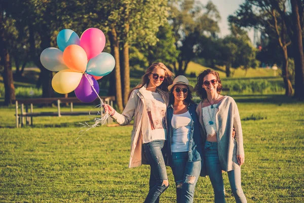 Gelukkige vrienden met regenboog-gekleurde lucht ballonnen — Stockfoto