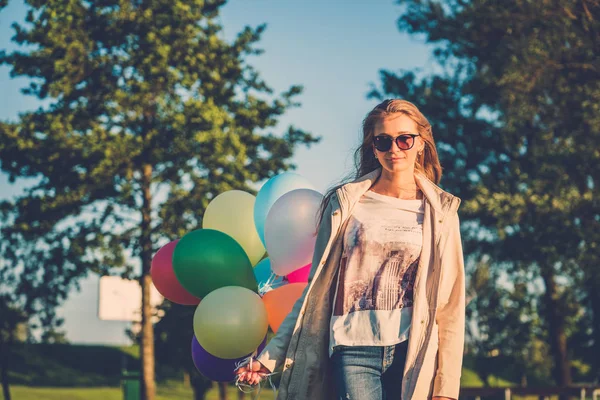 Menina feliz com balões de ar de cor arco-íris — Fotografia de Stock