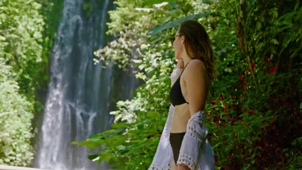 Женщина наслаждается днем возле водопада Лабухан Кебо, расположенного в Мундуке, Бали — стоковое видео