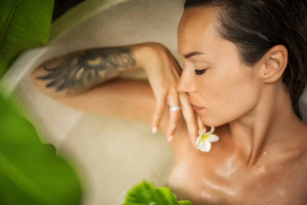 Woman relaxing in outdoor bath with tropical leaves at Bali — 스톡 사진