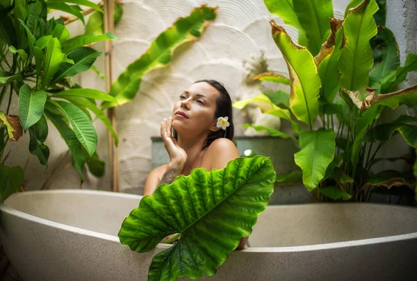 Mulher relaxante em banho ao ar livre com folhas tropicais em Bali — Fotografia de Stock