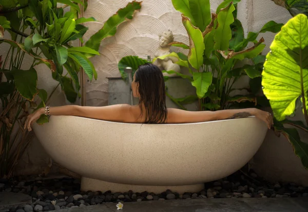 Kvinna avkopplande i utomhusbad med tropiska blad på Bali — Stockfoto