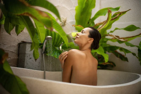 Mulher relaxante em banho ao ar livre com folhas tropicais em Bali — Fotografia de Stock