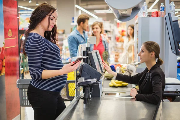 Ciężarna kobieta kupująca towary w sklepie spożywczym — Zdjęcie stockowe