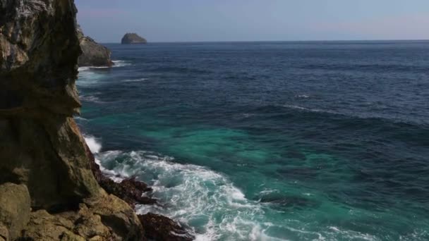 Волна разбивает скалу на берегу моря — стоковое видео