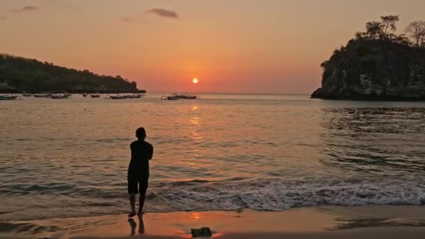 Человек рыбачит на закате в заливе Crsytal Bay, остров Нуса-Пенида, Индонезия — стоковое видео
