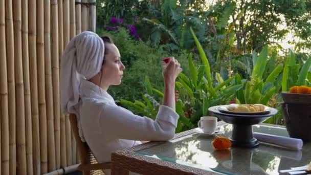 Vrouw geniet van koffie op terras in tropisch land — Stockvideo