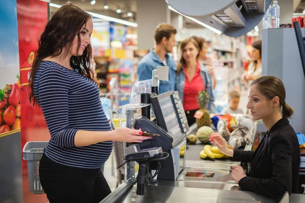 Ciężarna kobieta kupująca towary w sklepie spożywczym — Zdjęcie stockowe