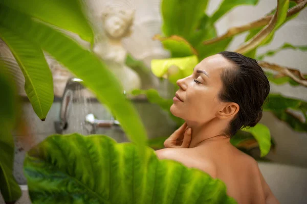 Vrouw ontspannen in buitenbad met tropische bladeren op Bali — Stockfoto